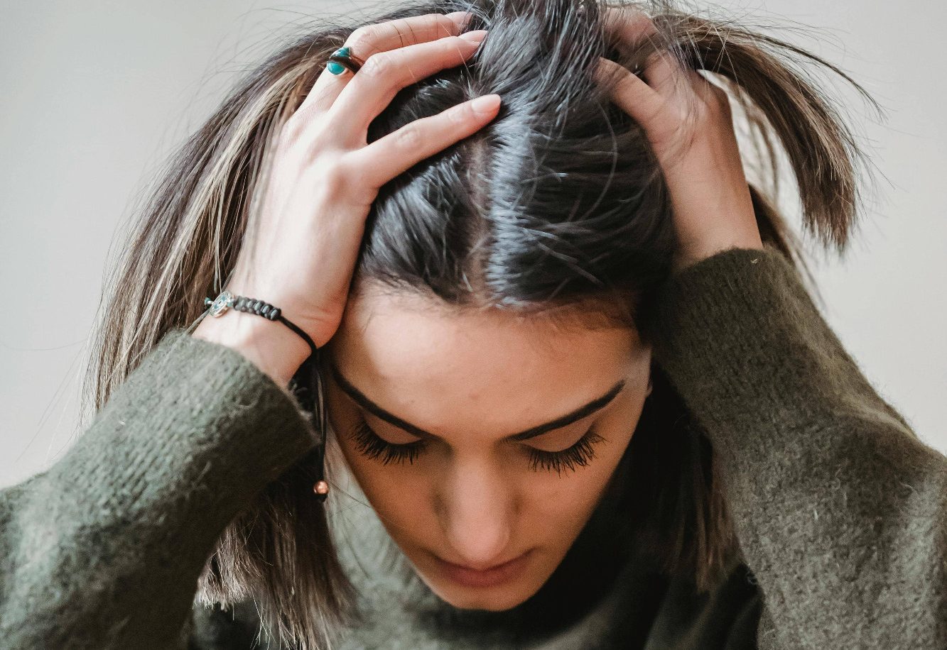 une jeune femme la tête dans les mains stressée