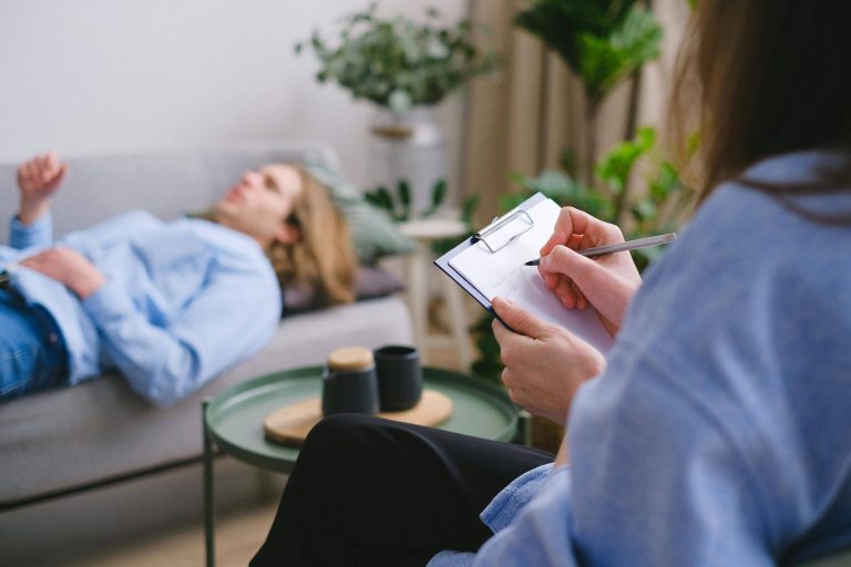un homme allongé qui parle devant une femme assise qui prend des notes