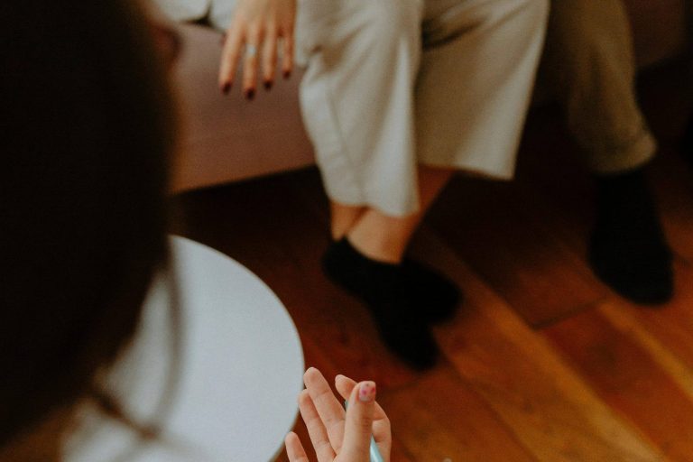 on distingue deux paires de jambes assise face à une femme qui prend des notes