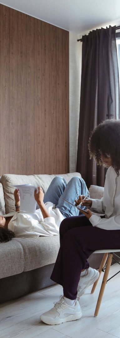 une femme allongée parle avec une femme assise qui prend des notes
